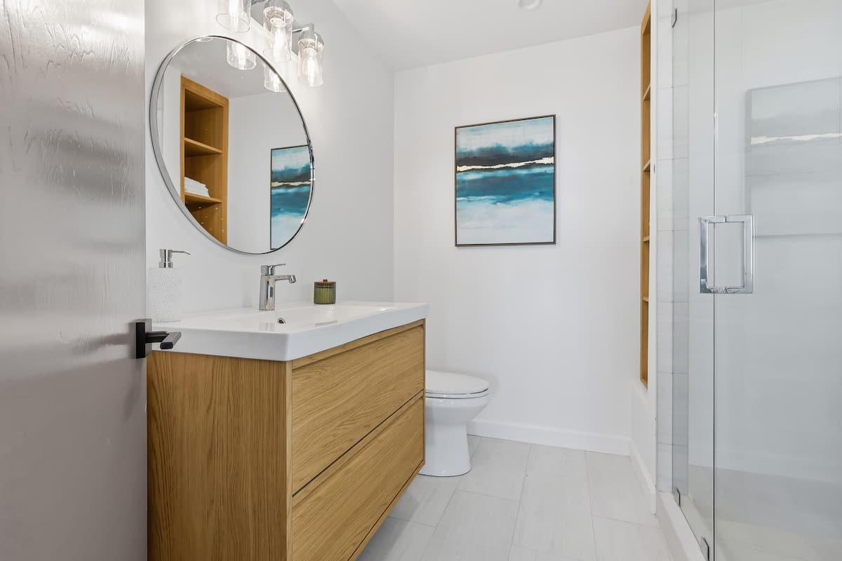 Guest bathroom with oak vanity and round mirror
