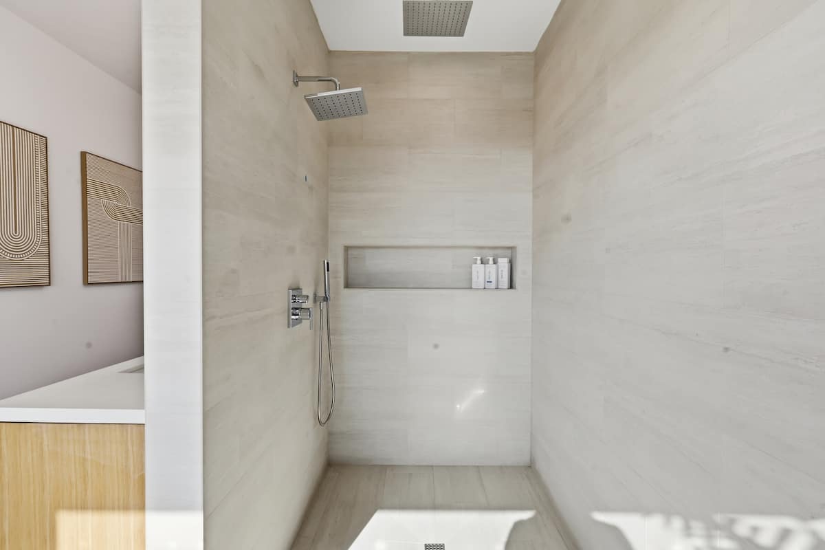 Glass rain shower with warm stone tile