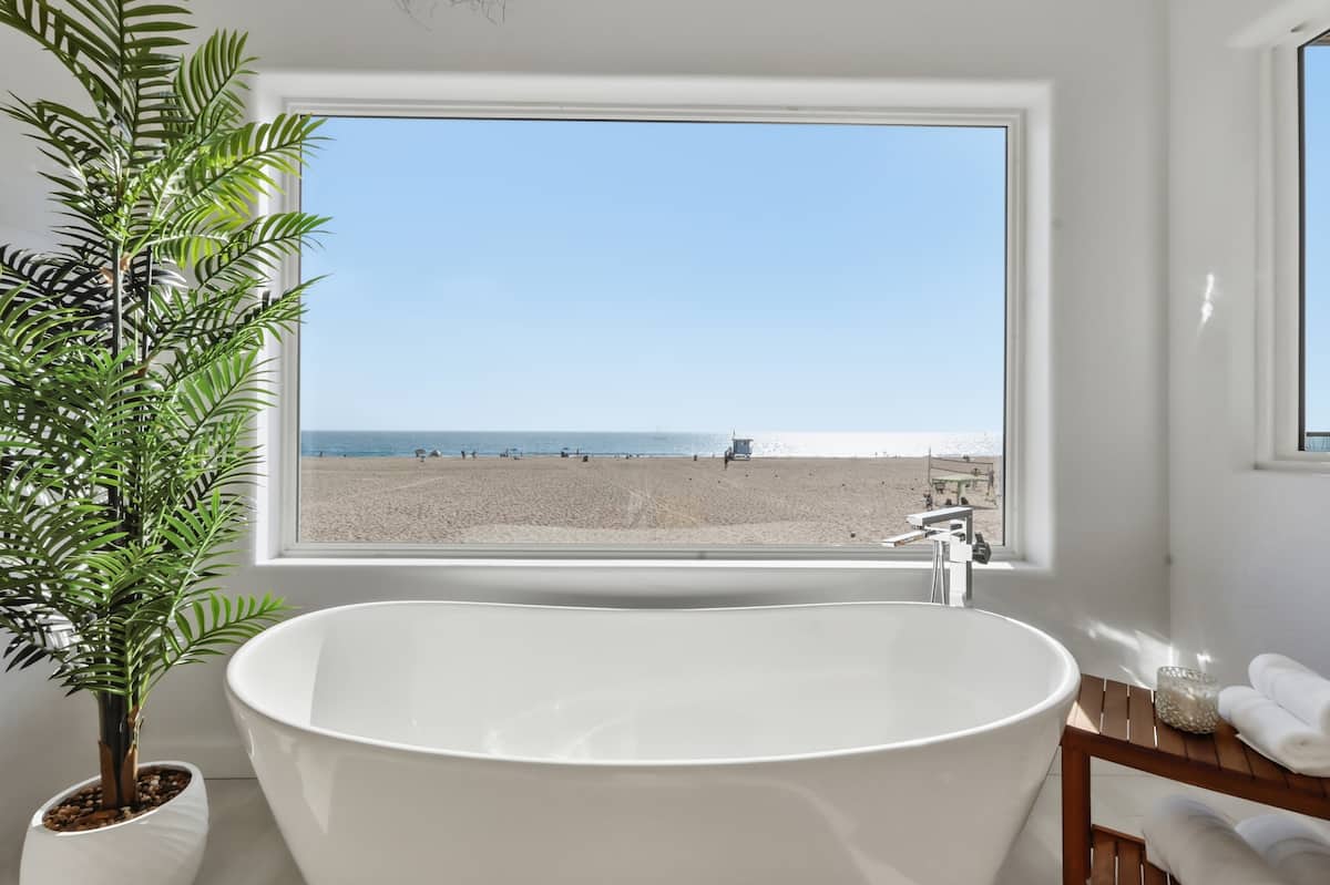 Freestanding bath beside a window framing the ocean